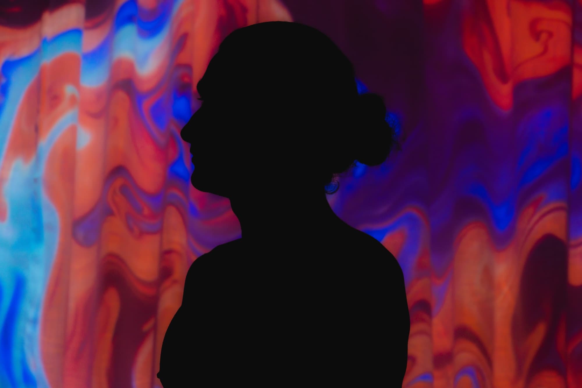 A breathwork practitioner silhouetted against the studio's projections